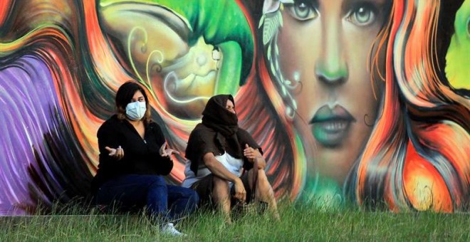 Dos mujeres cubren sus rostros debido a los gases lacrimógenos de un enfrentamiento entre manifestantes y la policía este viernes en Tegucigalpa (Honduras). EFE/Gustavo Amador