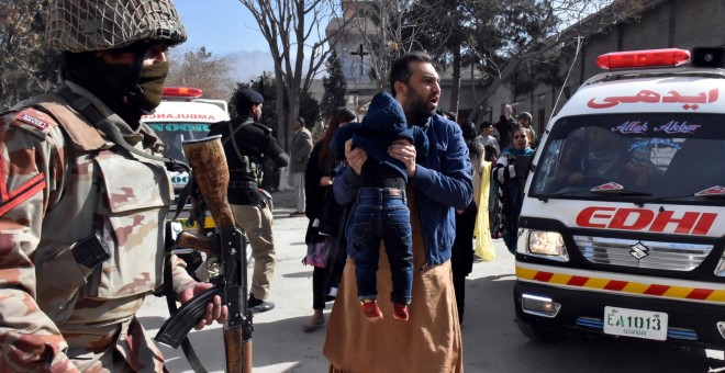 Un hombre sostiene a un niño ante un militar tras el ataque a una iglesia metodista en Pakistán. /EFE