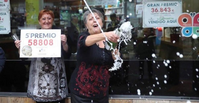 Las loteras María Jesus (d) y Begoña celebran el reparto del quinto premio de la lotería de Navidad, que le ha tocado al número 58808, en un punto de venta de la calle Castaños de la capital vizcaína. | LUIS TEJIDO (EFE)