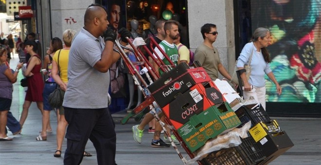 Un trabajador extranjero traslada una carretilla por el centro de Madrid. E.P.