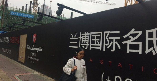 Una mujer pasea junto a una obra en Chengdu, China. REUTERS