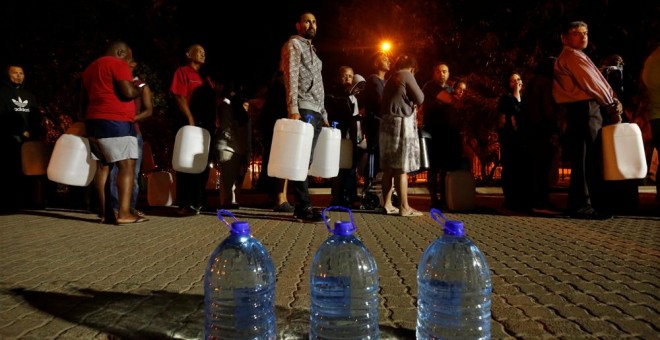 Varios ciudadanos hacen cola para recoger agua de una fuente en uno de los suburbios de Ciudad del Cabo. REUTERS