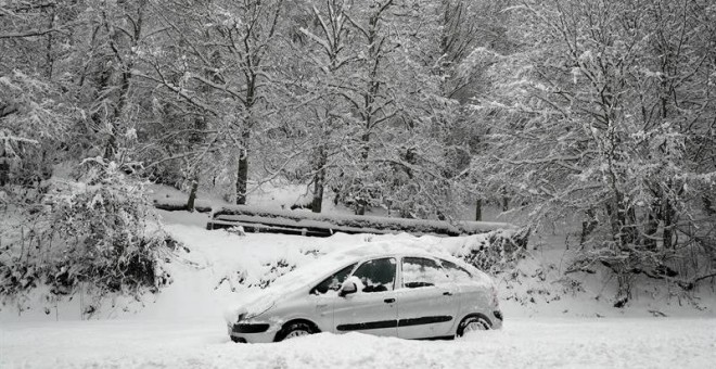 Un coche permanece atascado en la nieve en el Alto de Mezquiriz donde, tras el último temporal de nieve, frío y viento. /EFE