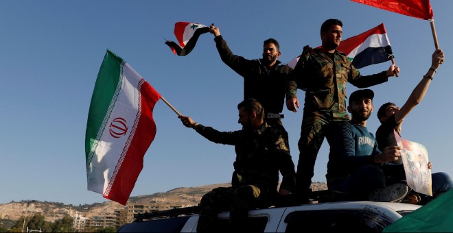 Sirios ondean las banderas de Irán, Rusia y Siria en protesta por los ataques en Damasco. /REUTERS