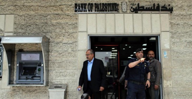 Un policía de Hamás gesticula ante la entrada de un banco en la ciudad de Gaza. | (REUTERS/Ibraheem Abu Mustafa)