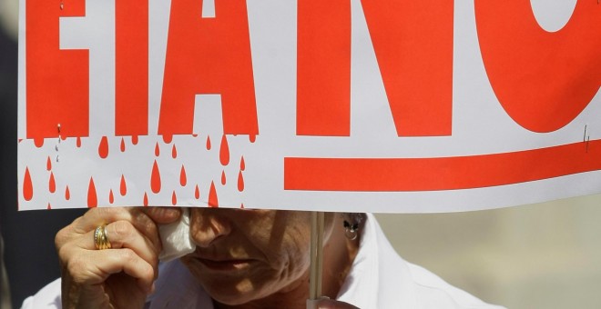 Un hombre solloza mientras sostiene una pancarta contra ETA en un minuto de silencio frente al Ayuntamiento de Madrid, tras un atentado de la organizacion terrorista en Mallorca en el que mató a dos guardias civiles, en julio de 2009. REUTERS/Susana Vera