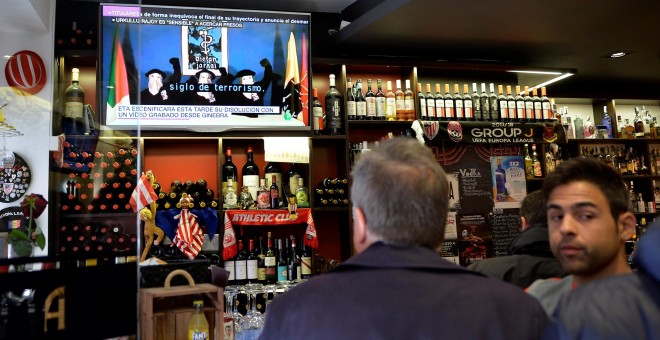 Varias personas en un bar en Bilabo miran la información en la televisión del anuncio del 'desmantelamiento total' de ETA. REUTERS/Vincent West