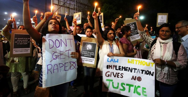 La gente sostiene velas y pancartas durante una protesta contra la violación de una niña de ocho años en Kathua/Reuters