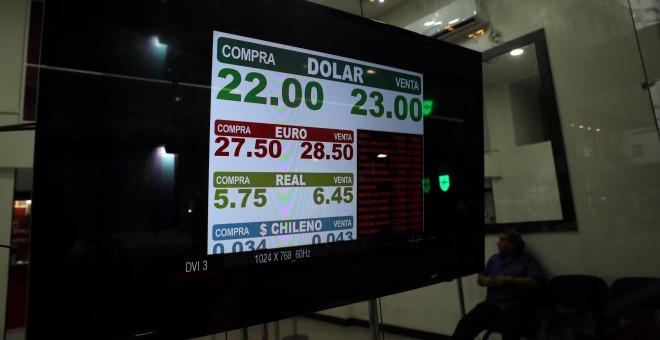 Un hombre, sentado en una casa de cambio en el distrito financiero de de Buenos Aires, donde un monitor muestra el tipo de cambio del dólar frente al peso. REUTERS/Marcos Brindicci