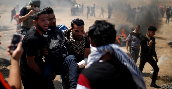 Varios palestinos trasladan a un herido en las protestas en Gaza contra la embajada de EEUU en Jerusalén. - REUTERS
