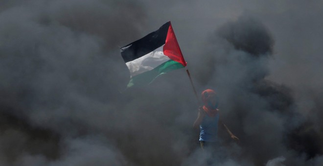 Un chico sostiene una bandera palestina en medio del humo durante las protestas contra el traslado de la embajada de EEUU a Jerusalén. / Reuters