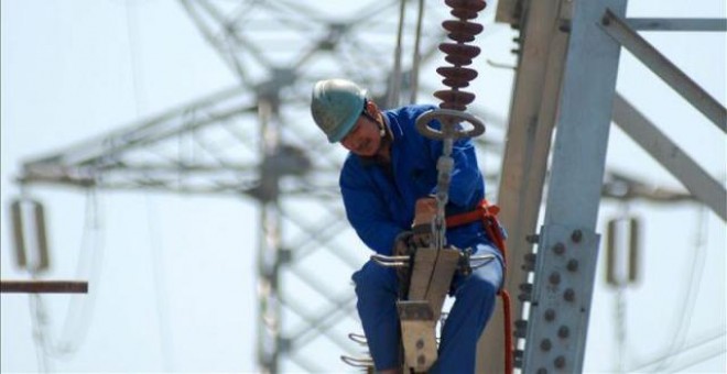 Un trabajador instala nuevas líneas de alto voltaje en una torre de electricidad. EFE/Archivo