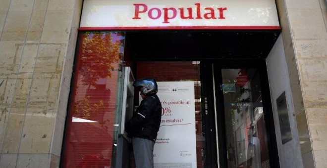 Un hombre saca dinero de un cajero automático del Banco Popular, en la localidad barcelonesa de Vilanova i la Geltru, en una foto del 7 de junio de 2017, el día que se anunció la resolución de la entidad. AFP/Lluis Gené
