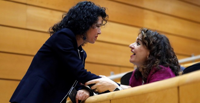 La ministra de Hacienda, María Jesús Montero, conversa con la senadora de Podemos, María Isabel Mora Grande, durante la sesión del Senado que debate los cinco vetos a los PGE de 2018. EFE/Juan Carlos Hidalgo