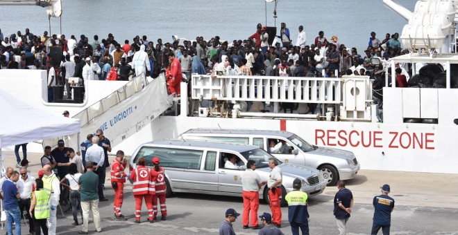 Dos coches funerarios aguardan a que varios oficiales desembarquen los cadáveres de dos inmigrantes a la llegada de la patrullera de la Guardia Costera Diciotti al puerto de Catania (Italia). EFE/ Orietta Scardino