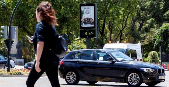 Una joven pasa junto a un termómetro que marca 35 grados centígrados en el Plano de San Francisco, Murcia. - EFE