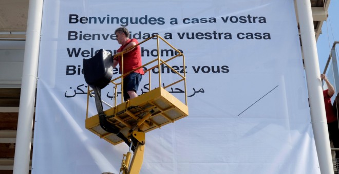 Un voluntario de la Cruz Roja coloca una pancarta para saludar a los migrantes del Aquarius en el puerto de Valencia. REUTERS/Heino Kalis