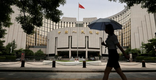 Una mujer camina frente al edificio del  People's Bank of China (PBOC) en Beijin./REUTERS