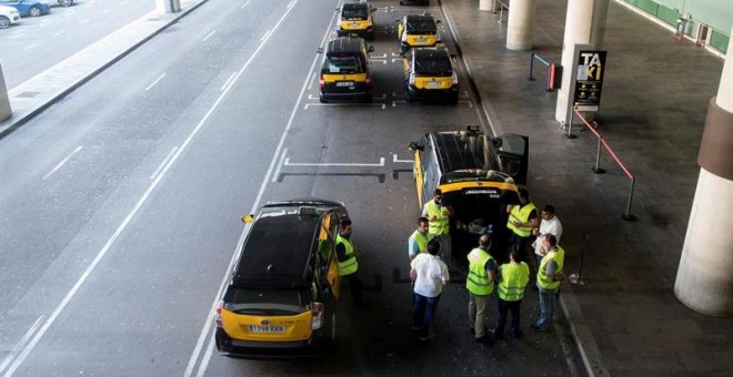 Un grupo de taxistas permanecen parados con sus vehículos en el Aeropuerto de Barcelona durante la huelga de taxis este miércoles. / EFE