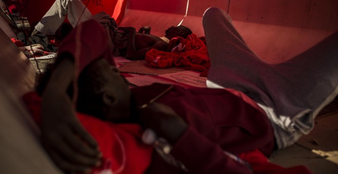 Dos migrantes se protegen del sol bajo una manta en el puerto del Algeciras. Han pasado varias noches allí debido al colapso en los polideportivos y dependencias policiales tras llegar en patera a España. JAIRO VARGAS