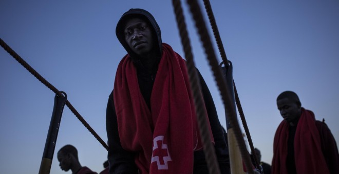 Un joven migrante sube a borde de un barco de Sasemar junto a otros 200 personas para pasar la noche tras ser rescatado de una patera durante el fin de semana. JAIRO VARGAS