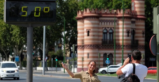 Una turista se fotografía bajo un termómetro que marca 50ºC hoy en Sevilla. EFE/Pepo Herrera