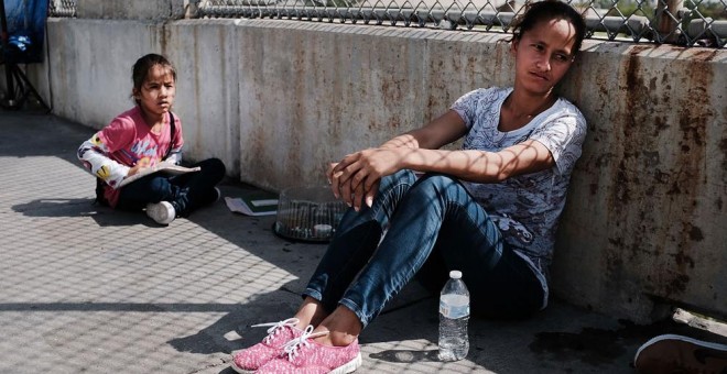 Una mujer hondureña y su hija que huyen de la violencia y la pobreza esperan en la frontera con EEUU tras haberles sido rechazada la entrada. SPENCER PLATT (AFP)