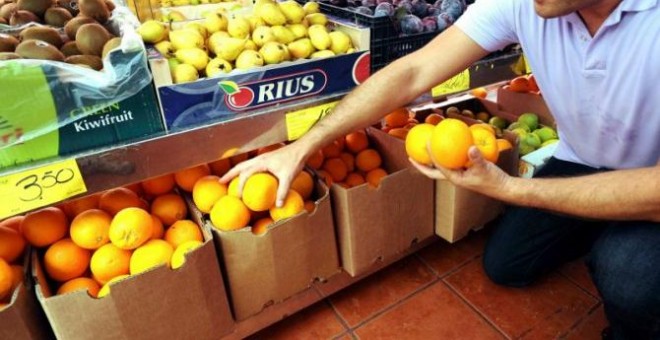 Un hombre al lado de unas naranjas en una frutería. EFE/Elvira Urquijo A.