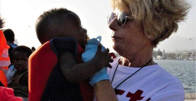 Un miembro de la Cruz Roja con uno de los menores rescatado en el mar de Alborán. (PEDRO FEIXAS | EFE)