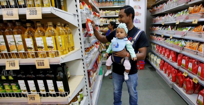Un hombre carga con su bebé en una mochila mientras que hace la compra en un supermercado de un centro comercial de la ciudad india de Calcuta. REUTERS/Rupak De Chowdhuri