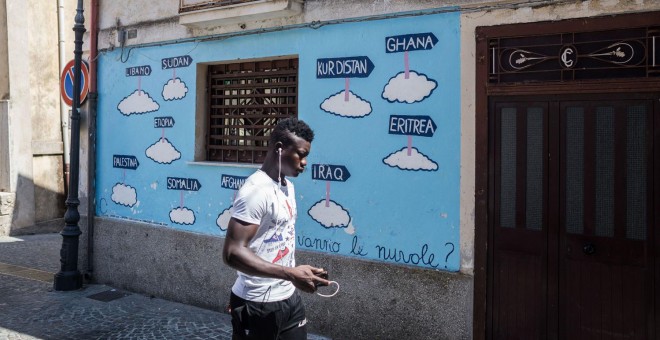 Un hombre pasa junto a un mural en Riace. - GIACOMO SINI