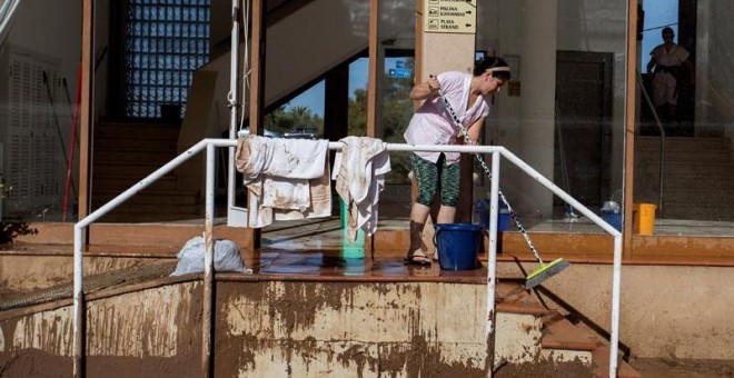 11/10/2018.- Una mujer en las tareas de limpieza en la desembocadura del torrente desbordado en S'Illot, Manacor, tras el temporal. EFE /LLITERES