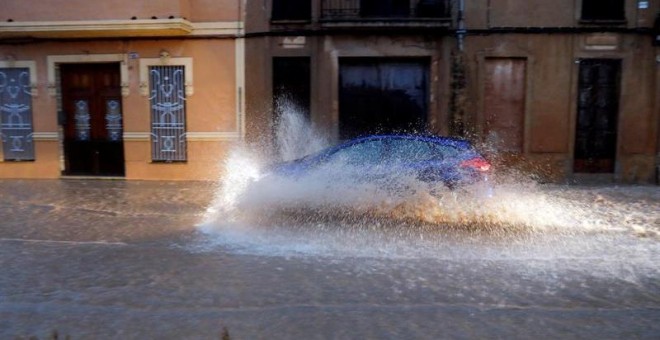 Un vehículo circula por una calle anegada en Valencia. - EFE