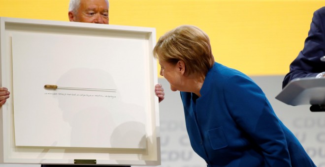 La canciller alemana, Angela Merkel, recibe la batuta del director de orquesta Kent Nagano como regalo de despedida durante el congreso de la CDU, en Hamburgo, en el que se decide su sucesor o sucesora al frente del partido. REUTERS / Fabrizio Bensch