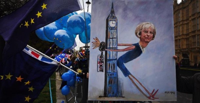 La artista Kaya Mar muestra un cuadro de la primer ministra británica Theresa May durante una manifestación en contra del brexit a las afueras del Parlamento en Londres. - EFE