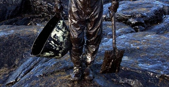 Un voluntario recoge el petróleo vertido por el Prestige. / ALBERTO ESTÉVEZ (EFE)