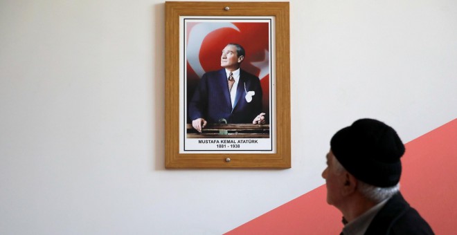 Un hombre pasa junto a un retrato del fundador del Estado turco, Mustafa Kemal Ataturk, en un colegio electoral en Estambul, en la jornada de elecciones locales. REUTERS/Kemal Aslan