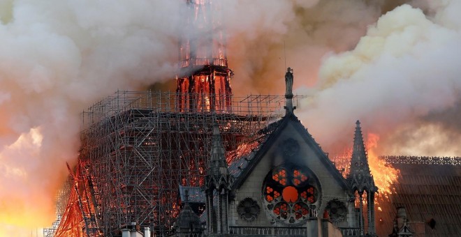 El humo ondea cerca de los andamios cuando el fuego envuelve la aguja de la catedral de Notre Dame. / Reuters