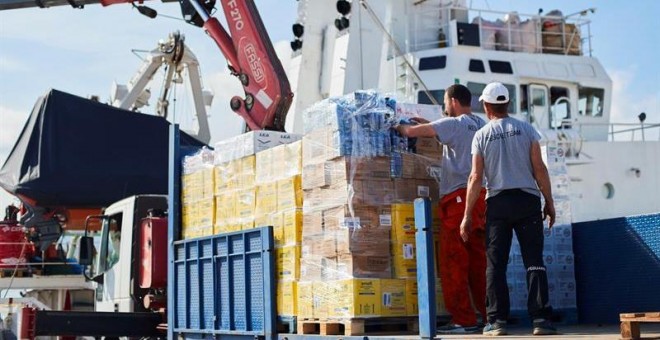 Operarios de Open Arms supervisan la carga de ayuda humanitaria al buque tras recibir la autorización para zarpar del puerto de Barcelona./ Alejandro García (EFE)