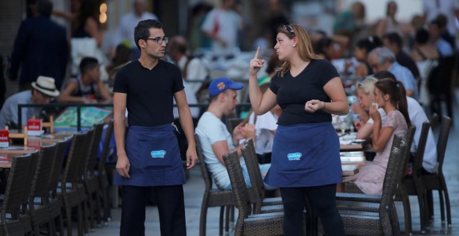 Una camarera conversa con un compañero de trabajo en una terraza de un restaurante en la localidad malagueña de Ronda. REUTERS/Jon Nazca