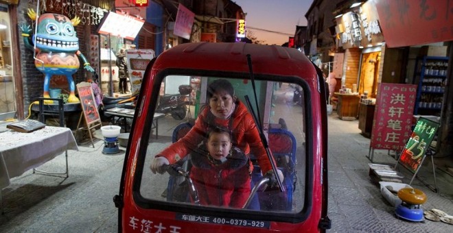 Una mujer y un niño en un triciclo eléctrico en la parte antigua de la ciudad de Luoyang, en la provincia china de Henan. REUTERS/Thomas Peter