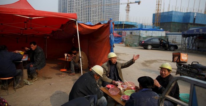 Los trabajadores almuerzan cerca del sitio de construcción de edificios de apartamentos cerca del nuevo estadio en Zhengzhou, en la provincia china de Henan. REUTERS / Thomas Peter