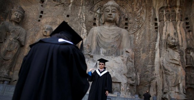 Jóvenes con su  vestidos de graduación se toman fotos frente a las estatuas de Buda en las grutas de Longmen, en Luoyang, en la provincia china de Henan. REUTERS / Thomas Peter
