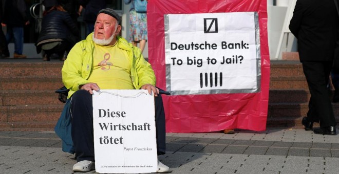 Un manifestante protesta en el exterior de la junta de accionistas de Deutsche Bank, en Fráncfort, con un cartel que dice 'Esta economía mata. El Papa Francisco'. REUTERS / Kai Pfaffenbach