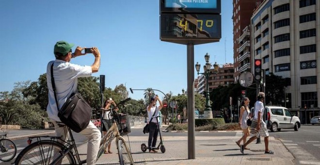 Varias personas fotografían un termómetro que marca 47 grados, este viernes en Valencia. EFE/Biel Aliño