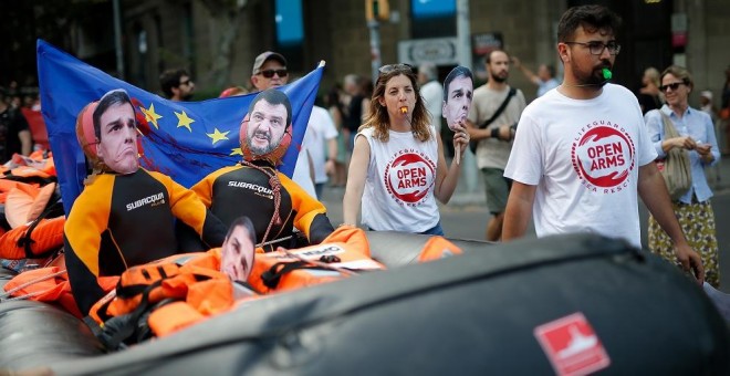 13/07/2019 - Manifestantes sostienen un bote hinchable con imágenes de las caras del presidente Pedro Sánchez y el ministro del Interior italiano, Matteo Salvini, en una protesta en Barcelona. / AFP - PAU BARRENA