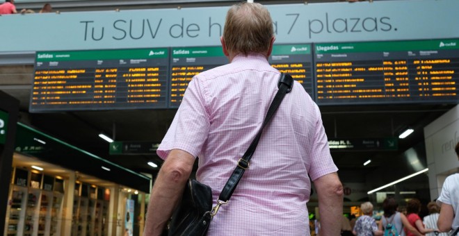 31/07/2019 - Un viajero espera frente a uno de los paneles de Salidas y Llegadas de la estación de trenes de Atocha