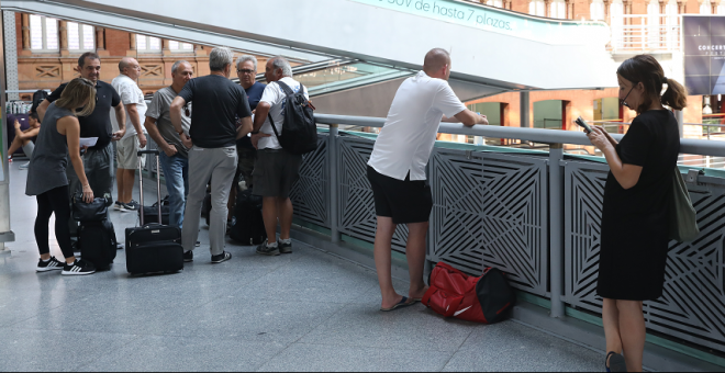 Varios pasajeros con sus maletas y en las escaleras mecánicas esperan en la estación de tren Puerta de Atocha de Madrid durante la primera de las cuatro jornadas de paros parciales de Renfe, el pasado 31 de julio. / Marta Fernández