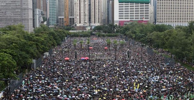 Una multitud se refugia de la lluvia bajo paraguas durante una nueva marcha contra el gobierno en Hong Kong. - EFE