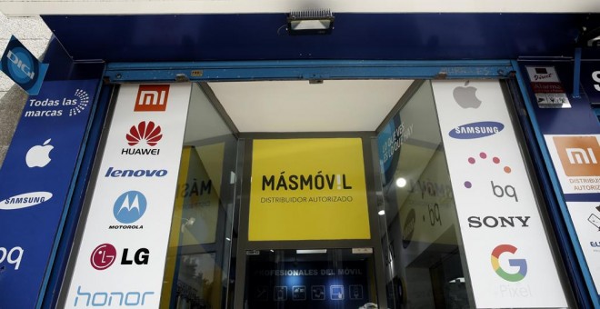 Exterior de una tienda de servicio técnico de móviles con un cartel publicitario de MásMóvil en color amarillo. E.P./Eduardo Parra
